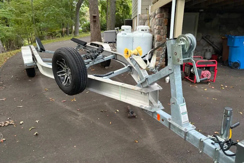 Slide: The Image of Trailer for 2024 Yamaha Boats 275SDX parked on driveway near garage. - 34
