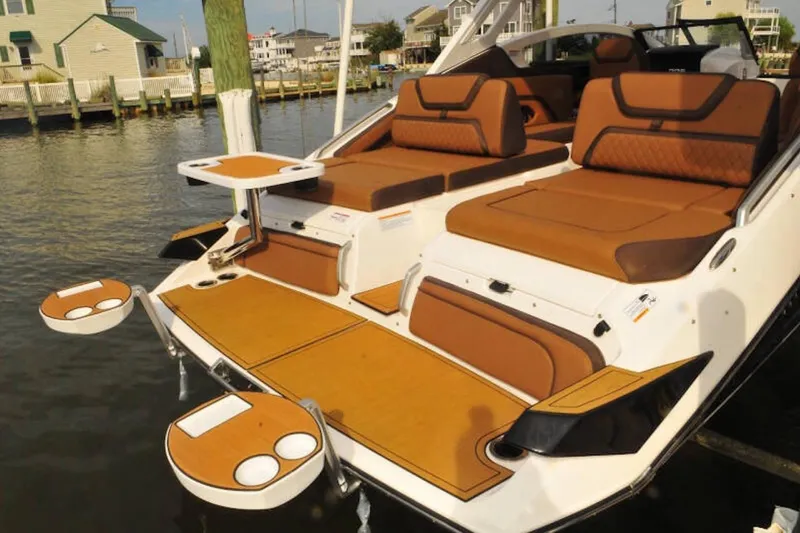 Slide: The Image of 2024 Yamaha Boats 275SDX with luxurious seating and cup holders on a sunny dock. - 7