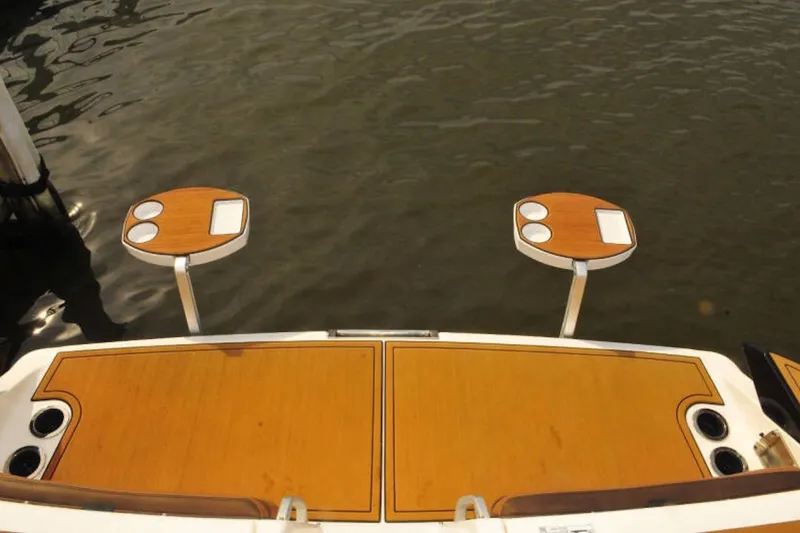 Slide: The Image of 2024 Yamaha Boats 275SDX swim platform with dual tables on water. - 8