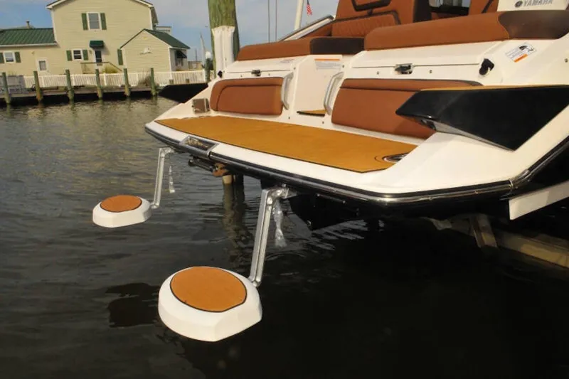 Slide: The Image of 2024 Yamaha Boats 275SDX with innovative swim platform and seating, docked by waterfront homes. - 9