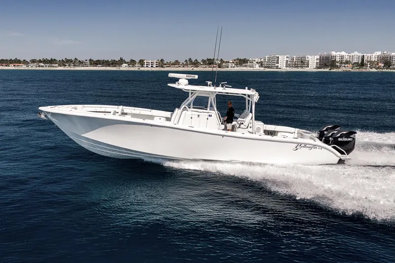 Slide: The Image of 2012 Yellowfin 39 Offshore boat cruising on open water near a coastal cityscape. - 17