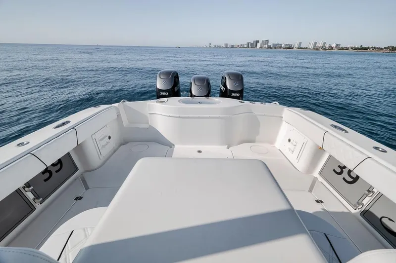 Slide: The Image of 2012 Yellowfin 39 Offshore boat with triple engines, cruising on open sea near city skyline. - 39