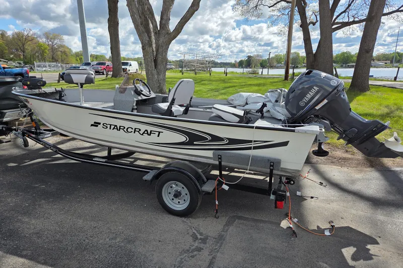The Image of 2023 Starcraft Patriot 16 SC boat with Yamaha motor on trailer, parked near a lake. - 0