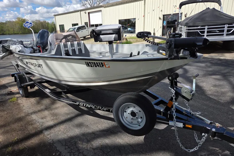 Slide: The Image of 2023 Starcraft Patriot 16 SC boat on trailer, parked outdoors near a building. - 2