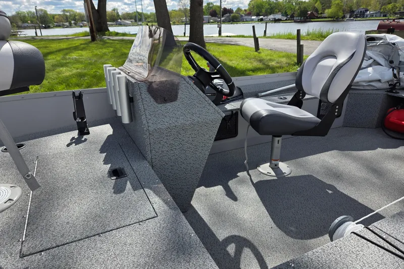Slide: The Image of 2023 Starcraft Patriot 16 SC boat interior with steering console and seating by a scenic lake. - 6