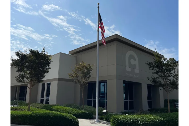 The Image of Modern building with American flag, clear sky, and trees; Novurania Deluxe 335, 2015. - 1
