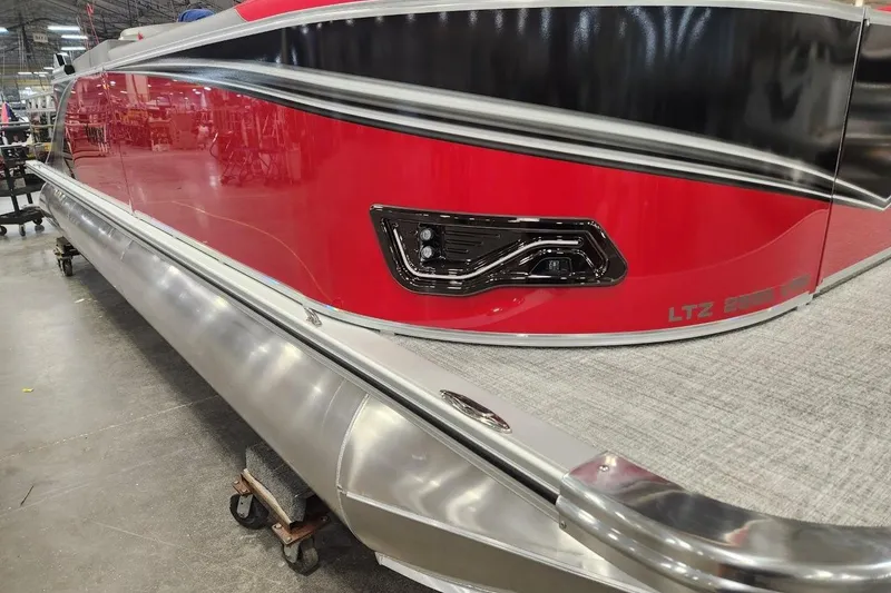 Slide: The Image of 2026 Tahoe Pontoon LTZ 2585 VRB with sleek red and black design in a showroom. - 5