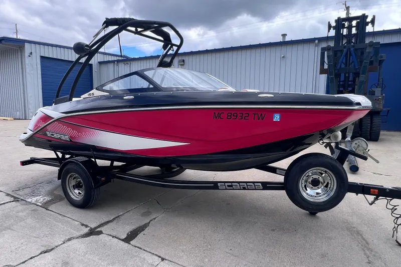 The Image of 2014 Scarab 195 H.O. boat in vibrant pink on a trailer, parked outdoors. - 1