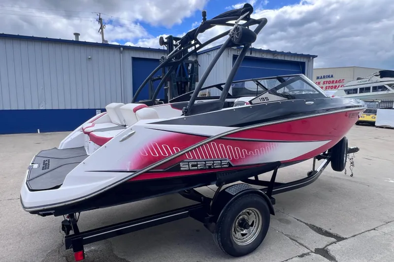 Slide: The Image of 2014 Scarab 195 H.O. boat with red and white design on a trailer. - 2