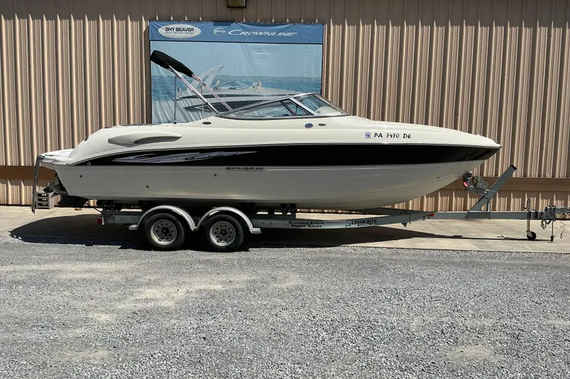 The Image of 2010 Stingray 250 LR boat on trailer, parked outdoors. - 1