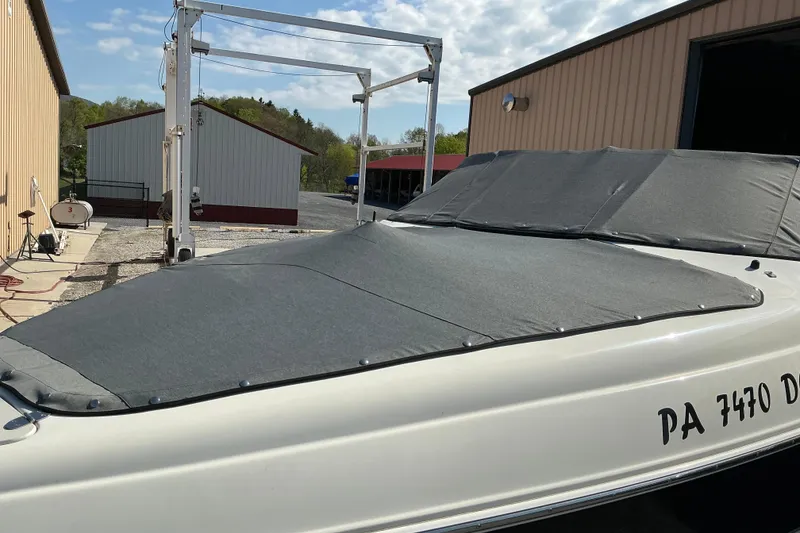 Slide: The Image of 2010 Stingray 250 LR boat with cover, parked near storage buildings. - 19