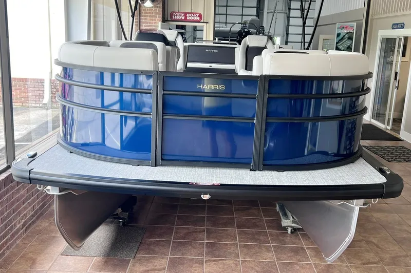 Slide: The Image of 2026 Harris Cruiser 210 SLDH pontoon boat displayed in showroom, featuring sleek blue design. - 2