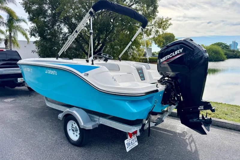 Slide: The Image of 2022 Bayliner Element M17 boat with Mercury engine on trailer, parked near a lake. - 2