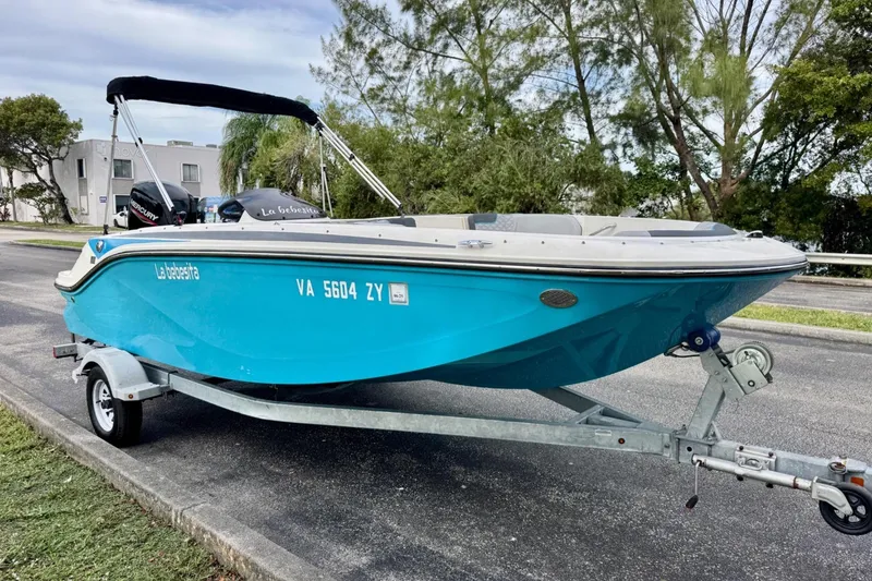 Slide: The Image of 2022 Bayliner Element M17 boat on trailer, vibrant blue hull, parked roadside. - 6
