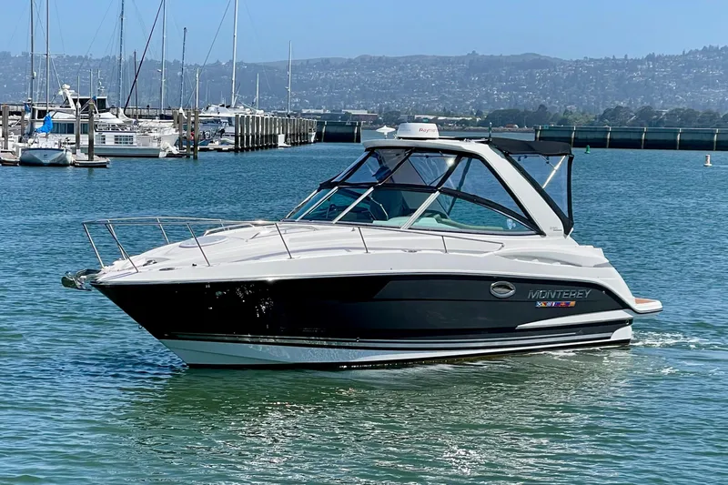 Slide: The Image of 2019 Monterey 295 Sport Yacht cruising in a marina with scenic background. - 1