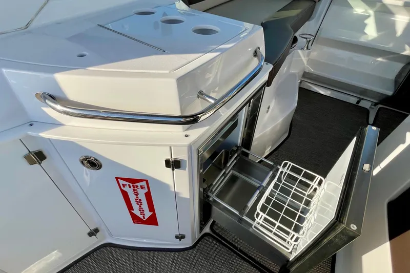 Slide: The Image of 2019 Monterey 295 Sport Yacht interior with open storage compartment and fire extinguisher sign. - 19