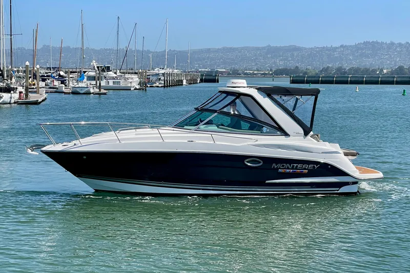 Slide: The Image of 2019 Monterey 295 Sport Yacht cruising in a marina with scenic background. - 2