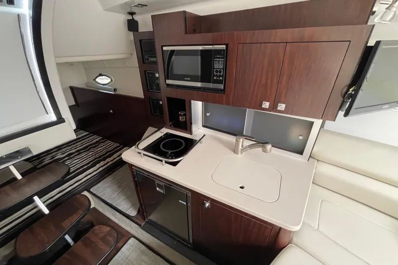 Slide: The Image of 2019 Monterey 295 Sport Yacht interior with kitchenette, featuring stove, sink, and microwave. - 21