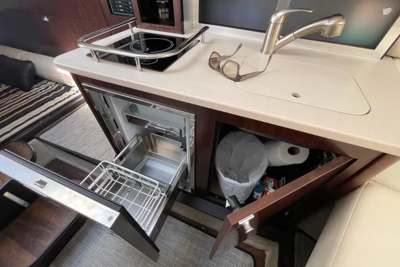 Slide: The Image of 2019 Monterey 295 Sport Yacht interior kitchen with sink, stove, and storage compartments. - 22
