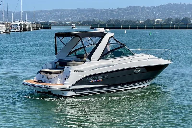 Slide: The Image of 2019 Monterey 295 Sport Yacht cruising on a calm bay with scenic background. - 5
