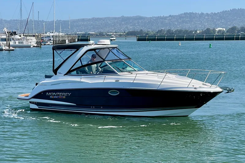 Slide: The Image of 2019 Monterey 295 Sport Yacht cruising in a marina with scenic background. - 7