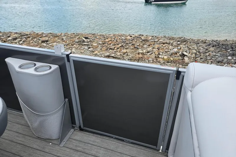 Slide: The Image of 2020 Bentley Pontoons 220 Elite interior with cup holders, near rocky shoreline. - 13