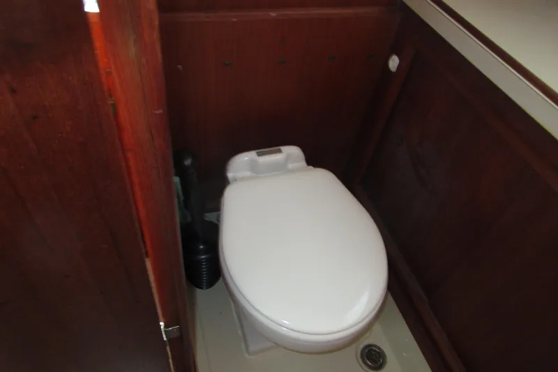 Slide: The Image of 1984 Tollycraft 26 Sedan boat bathroom with white toilet and wooden paneling. - 16
