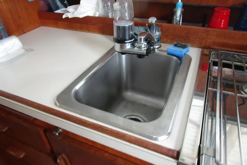 Slide: The Image of 1984 Tollycraft 26 Sedan kitchen sink with faucet and cleaning supplies. - 7