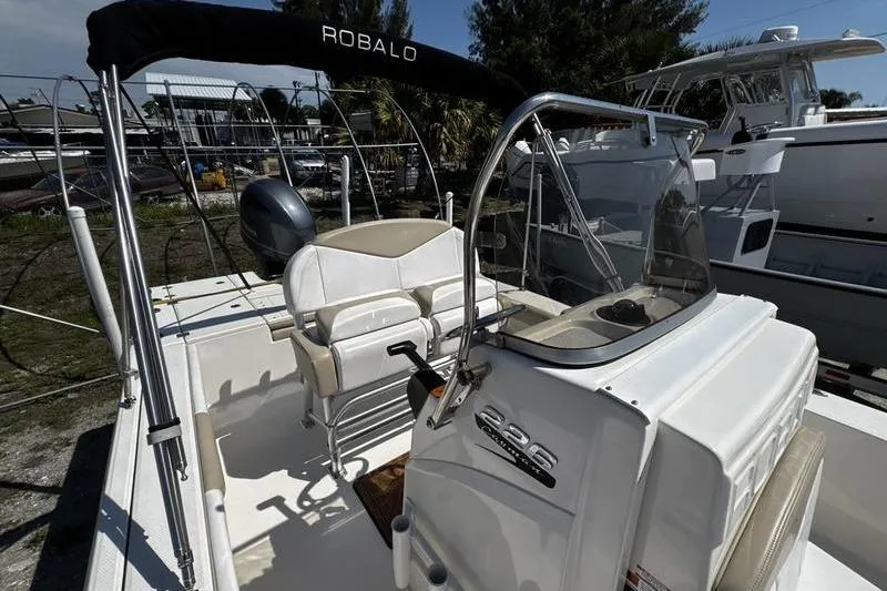 Slide: The Image of 2018 Robalo 226 Cayman boat interior with console and seating, docked outdoors. - 12