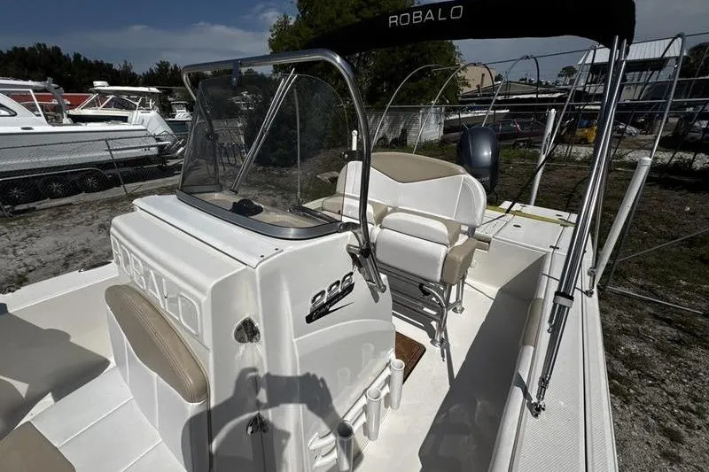 Slide: The Image of 2018 Robalo 226 Cayman boat interior with console and seating, parked outdoors. - 13