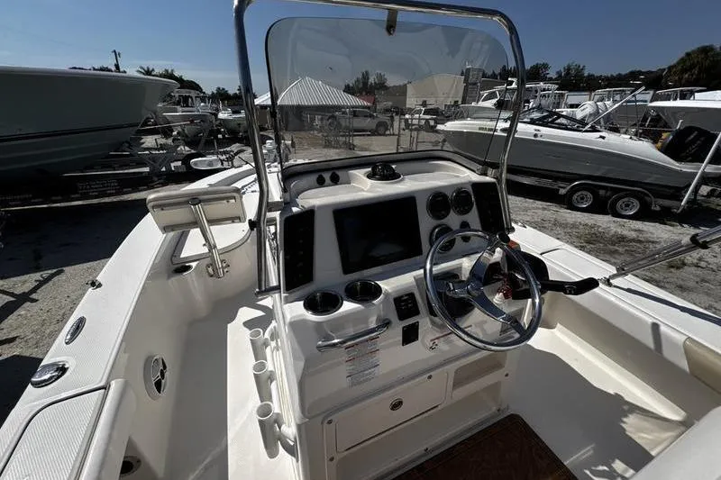 Slide: The Image of 2018 Robalo 226 Cayman boat dashboard with steering wheel and controls in a marina setting. - 16