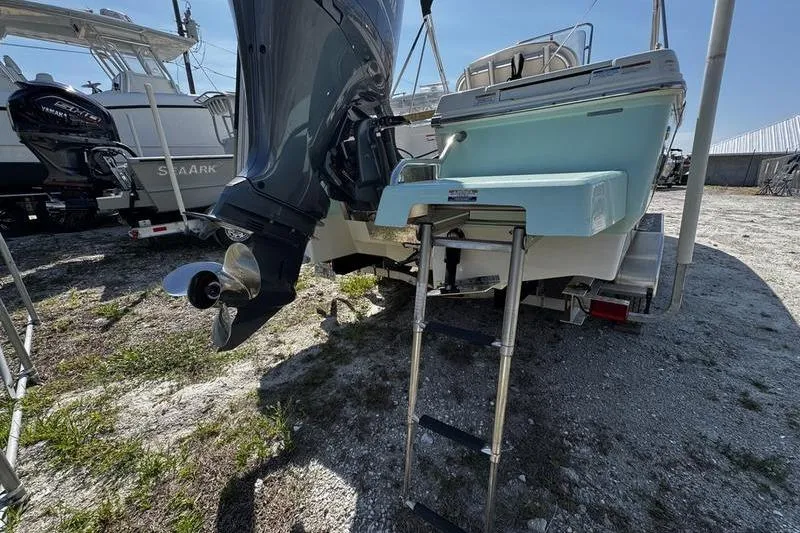 Slide: The Image of 2018 Robalo 226 Cayman boat with outboard motor and ladder, parked on gravel. - 5
