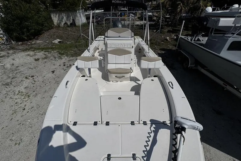 Slide: The Image of 2018 Robalo 226 Cayman boat with spacious deck and seating, parked outdoors. - 9
