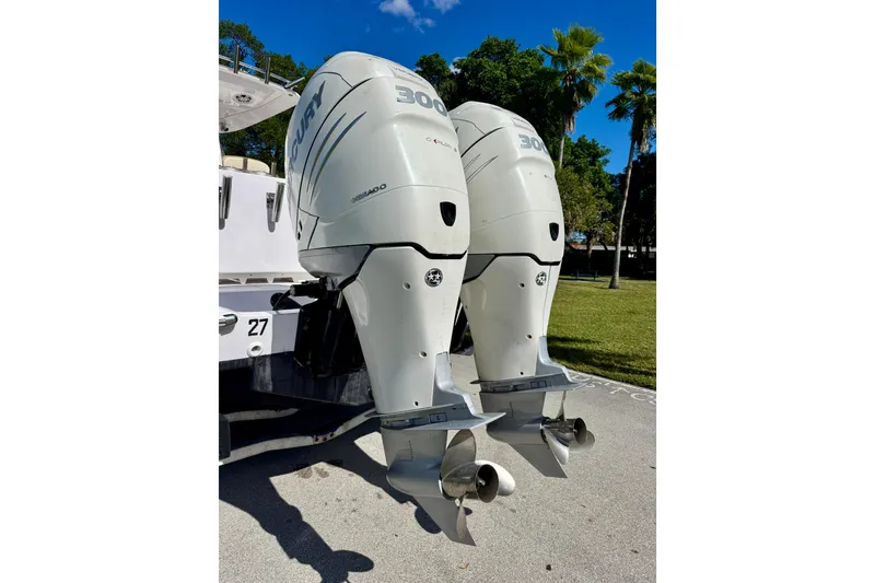 Slide: The Image of Twin Mercury outboard engines on a 2013 Belzona 32 CC boat, parked outdoors. - 12