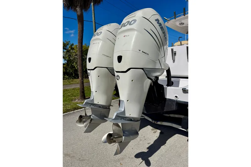 Slide: The Image of Twin Mercury outboard engines on a 2013 Belzona 32 CC boat, parked outdoors. - 13