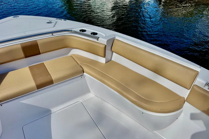 Slide: The Image of 2013 Belzona 32 CC boat with tan cushioned seating, docked on calm water. - 16