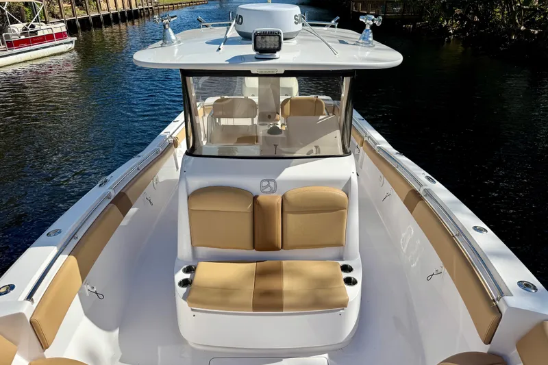 Slide: The Image of 2013 Belzona 32 CC boat with tan seating, docked on a calm waterway. - 18