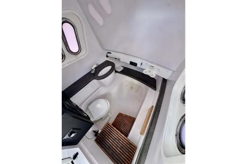 Slide: The Image of Interior of 2013 Belzona 32 CC boat, featuring a compact, modern bathroom with wooden flooring. - 27