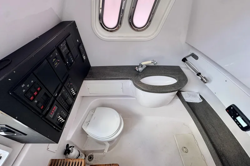 Slide: The Image of Interior of 2013 Belzona 32 CC boat featuring a compact bathroom with sink and control panel. - 28