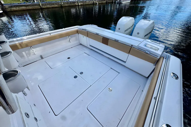 Slide: The Image of 2013 Belzona 32 CC boat deck with twin Mercury engines, docked by the water. - 33