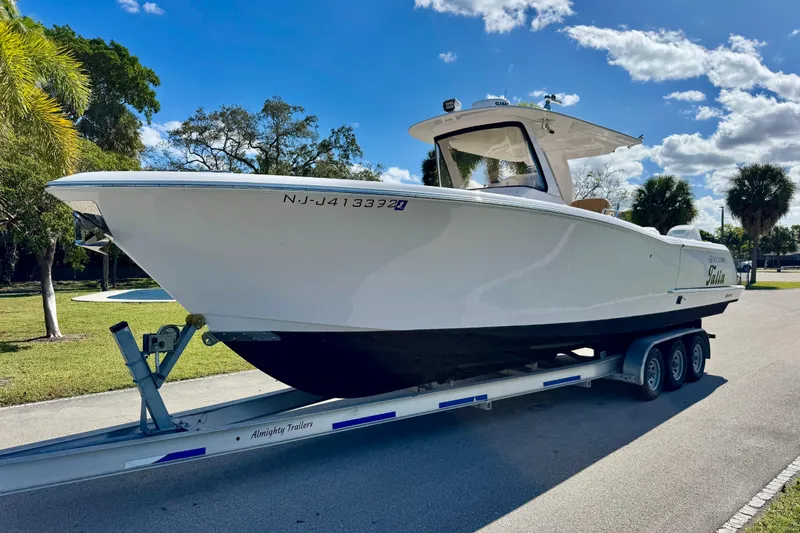 Slide: The Image of 2013 Belzona 32 CC boat on trailer, parked outdoors under a clear blue sky. - 6