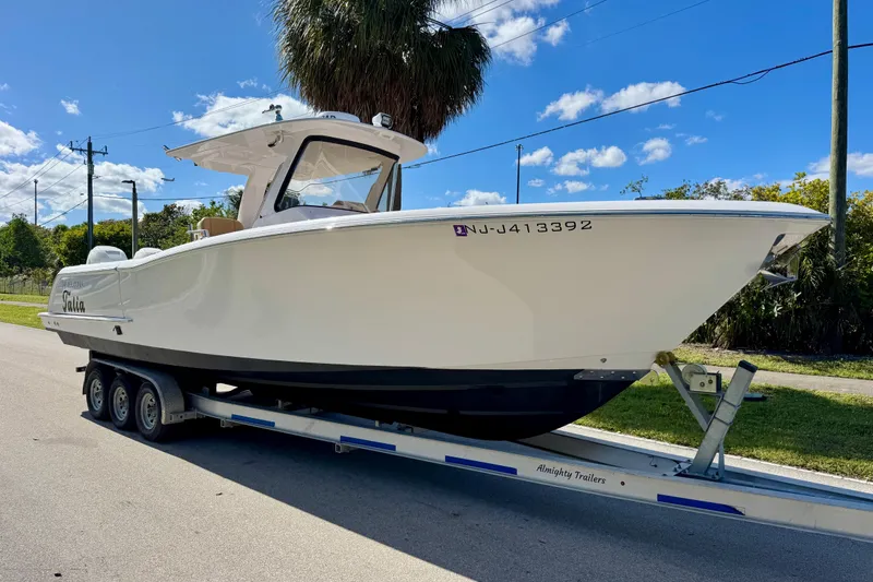 Slide: The Image of 2013 Belzona 32 CC boat on trailer under clear blue sky. - 7