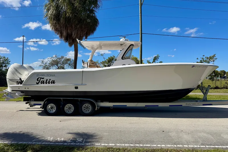 Slide: The Image of 2013 Belzona 32 CC boat on trailer, parked roadside under clear blue sky. - 8