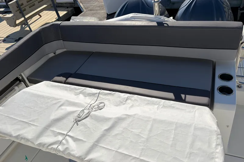 Slide: The Image of 2024 Jeanneau Leader 9.0 CC boat seating area with cup holders and protective cover. - 10