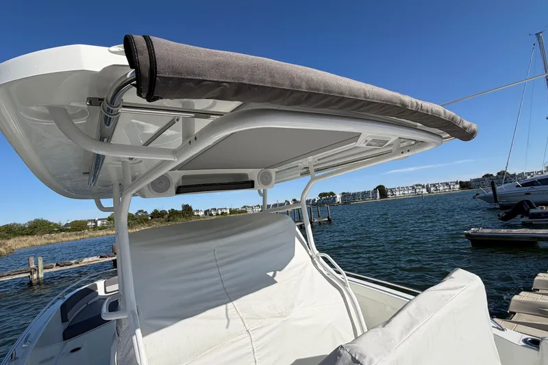Slide: The Image of 2024 Jeanneau Leader 9.0 CC boat with canopy, docked by the water on a sunny day. - 11