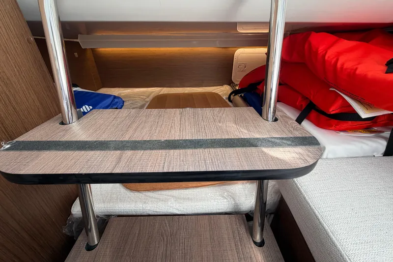 Slide: The Image of 2024 Jeanneau Leader 9.0 CC cabin interior with wooden table and life jackets. - 17