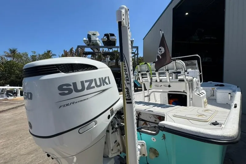 Slide: The Image of 2005 Kenner 21 VX boat with Suzuki 150 four-stroke engine, docked near a warehouse. - 3