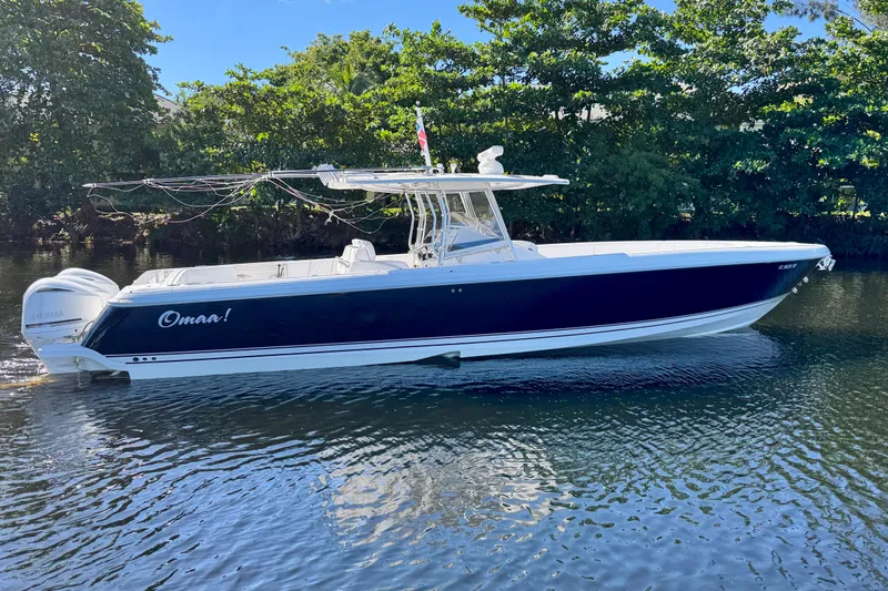 Slide: The Image of 2012 Intrepid 400 Center Console boat on calm water, surrounded by lush greenery. - 2