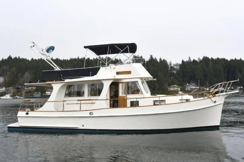 The Image of 1991 Grand Banks 36 Europa yacht on calm water with forested shoreline background. - 0