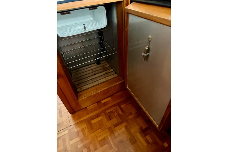 Slide: The Image of Open refrigerator inside 1991 Grand Banks 36 Europa yacht, featuring wooden flooring and metal door. - 24